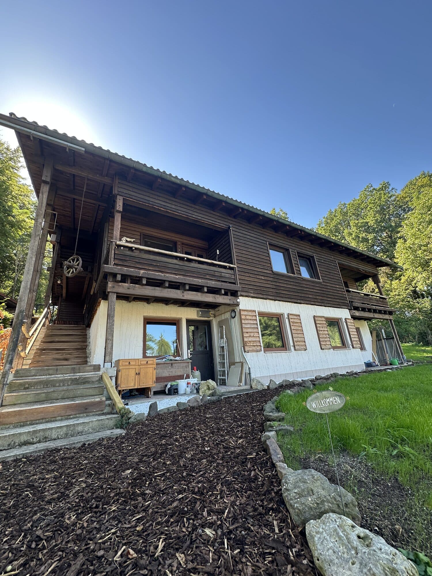 Eingang des Holzhauses mit Treppe zum Balkon und WILLKOMMEN-Schild
